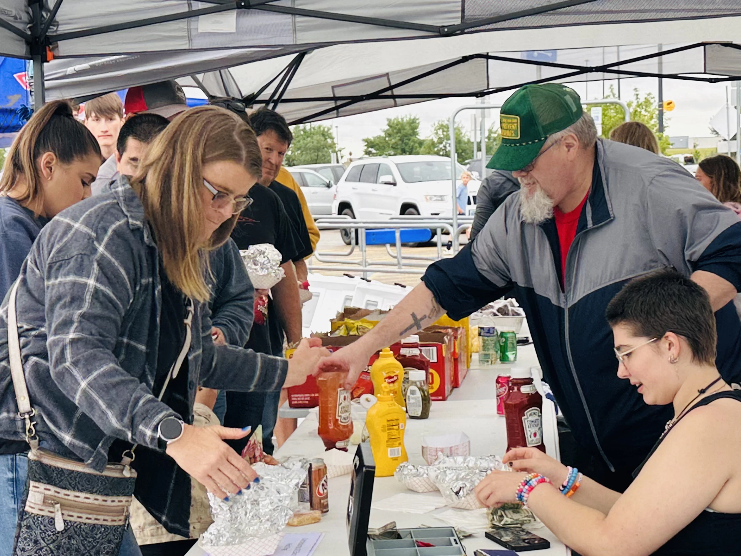Volunteers serving food under a tent at the community car show